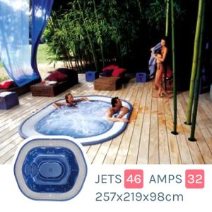 Outdoor wooden-deck hot tub with two people relaxing; bamboo garden and lounge area in background; inset shows blue interior jets and product specs (46 jets, 32 amps, 257×219×98 cm).