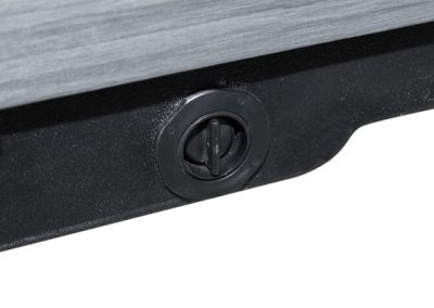 Close-up of a black circular dial with a vertical slot on a black base beside a gray panel.