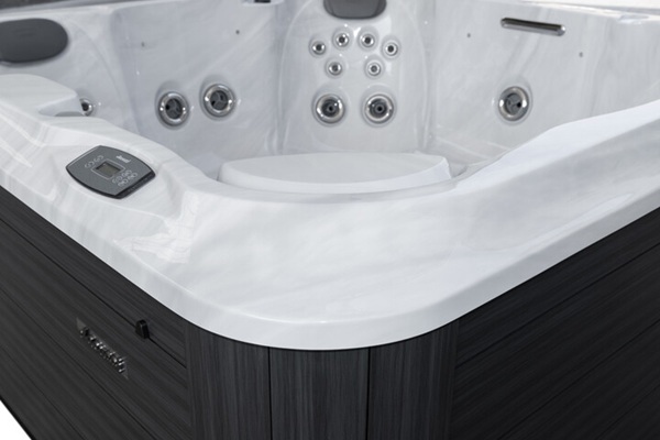 White acrylic hot tub with multiple jets and built-in seating, viewed from the corner with a control panel on the side.