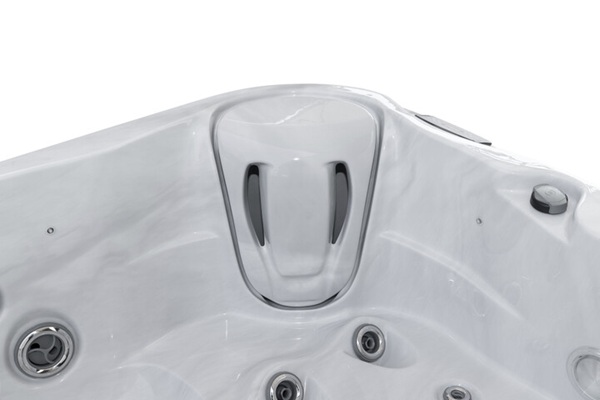 White hot tub interior with a raised central headrest area and several circular jets along the sides.