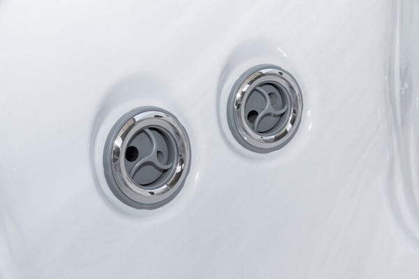 Close-up of two chrome bathtub jets embedded in a white surface.