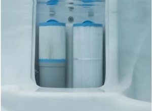 Two cylindrical water filter cartridges inside a white housing with blue caps, part of a home filtration system.
