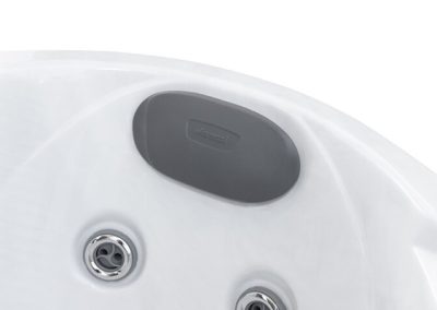 White hot tub shell with a dark gray oval control panel and two chrome jet openings nearby.
