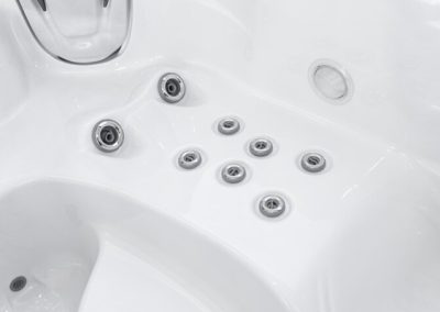 White hot tub interior showing several round silver jets embedded in the glossy surface.