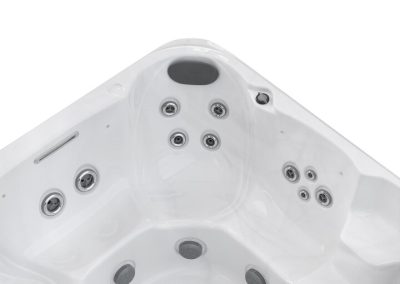 White hot tub interior with several circular jets and a black headrest at the top center.
