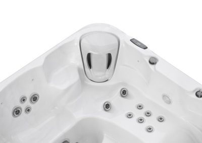 White corner hot tub with multiple water jets and a built-in headrest, seen from above edge view, empty of water