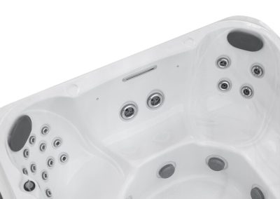 White corner hot tub/spa with multiple jet nozzles and built-in seating, viewed from above.