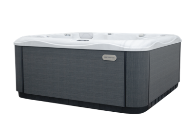 Rectangular outdoor hot tub with dark gray panels and a white interior, brand badge on the side, shown from the front-left.