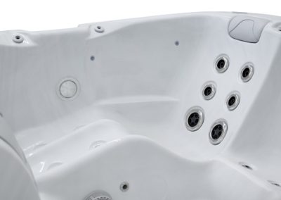 White hot tub interior with built-in seating and a cluster of round jet nozzles on the right side