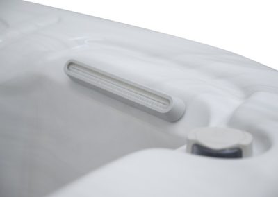 Close-up of a white inflatable mattress showing a recessed horizontal air valve and a nearby round control knob.
