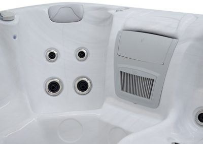 White hot tub interior with four jet nozzles arranged in a 2x2 grid and a built-in gray control panel on the right side, plus a cushioned headrest.