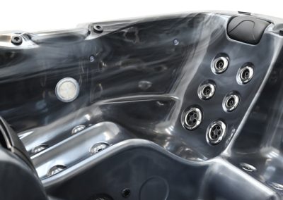 Interior of a glossy dark gray hot tub with built-in seating and multiple silver jets on the side panel