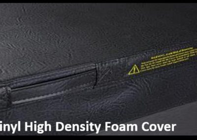 Close-up of a black vinyl high-density foam cover with a seam and a small yellow warning label.